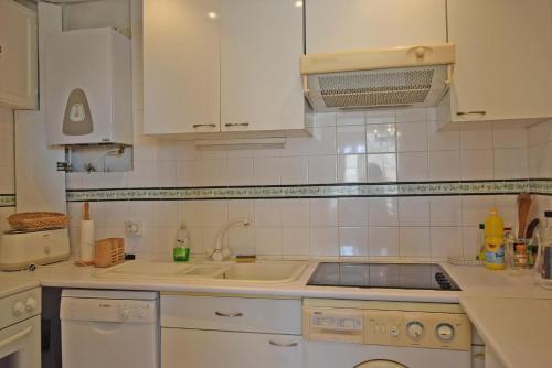 une cuisine avec des armoires blanches et un évier dans l'établissement Palais Alexandre III, à Cannes