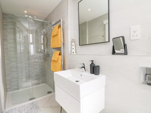 a white bathroom with a sink and a shower at Sea Breeze in Marazion