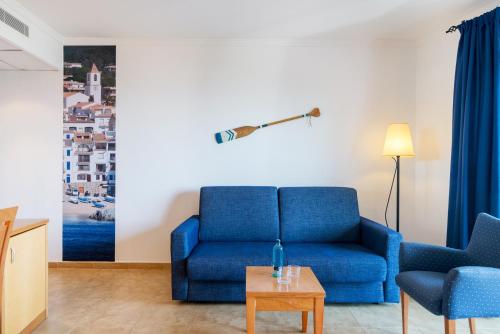 a living room with a blue couch and a table at Hotel Garbi in Calella de Palafrugell