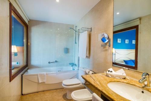 a bathroom with a tub and a toilet and a sink at Hotel Garbi in Calella de Palafrugell