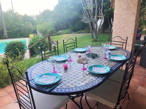 une table bleue avec des assiettes et des verres sur une terrasse dans l'établissement Villa avec piscine au Lavandou dans jardin méditerranéen, au Lavandou