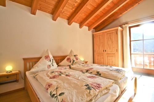 um quarto com uma cama com lençóis florais e uma janela em Ferienwohnungen Wanderparadies Bauernhof em Aschau im Chiemgau