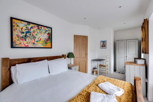 a bedroom with a large white bed and a kitchen at Tasteful 3-Bedroom House with private parking - Florence Park in Oxford