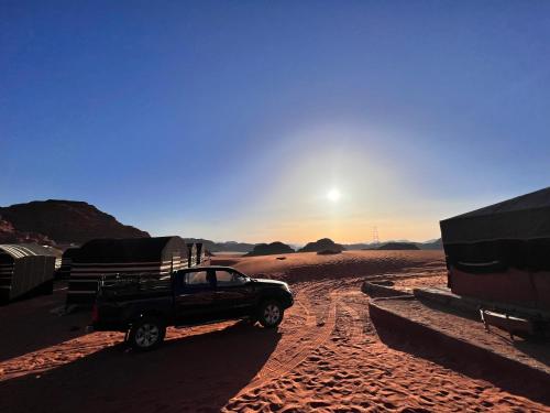 a truck parked in the desert with the sun setting at Wadirum Zeid camp&Tours in Wadi Rum