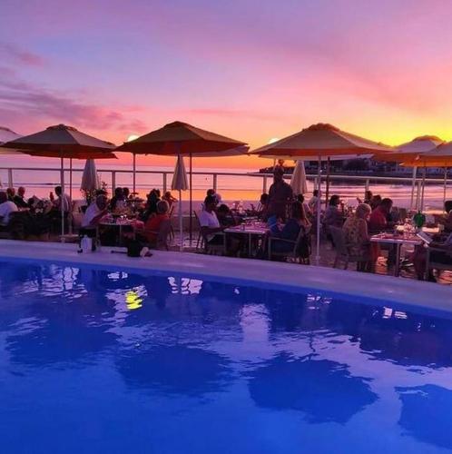 une piscine avec des gens assis à des tables et des parasols dans l'établissement Royan - Agréable Duplex Plage de Nauzan, à Vaux-sur-Mer