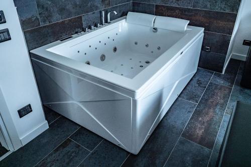 a large white bath tub in a bathroom at My Suite Hotel in LʼAquila