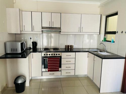 cocina con armarios blancos y fogones en E & P Cave en Swakopmund