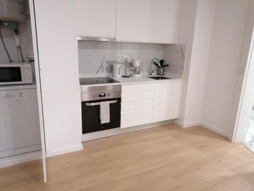 een kleine keuken met witte kasten en een fornuis bij TMJ Apartamento in Porto