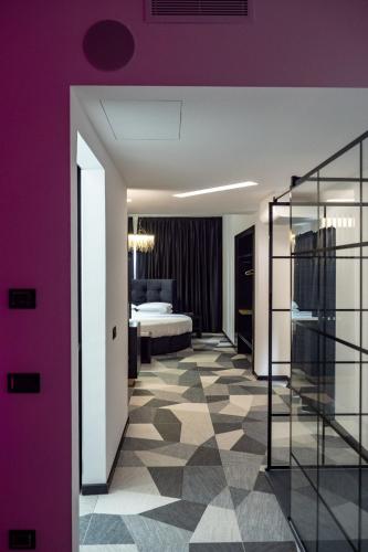 a bedroom with a bed and a purple wall at My Suite Hotel in LʼAquila