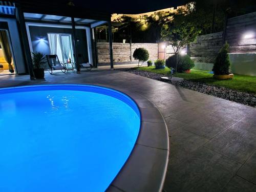 a large swimming pool in a backyard at night at Holiday house Boost with heated pool in Klis