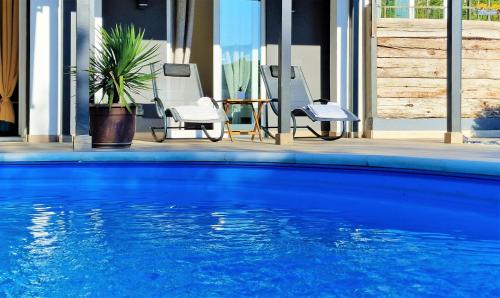 a blue swimming pool with chairs and a table at Holiday house Boost with heated pool in Klis