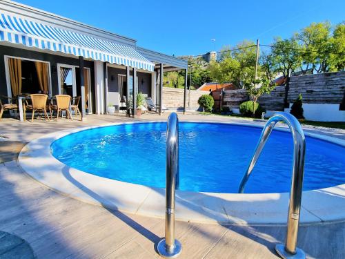 a swimming pool in a yard next to a house at Holiday house Boost with heated pool in Klis
