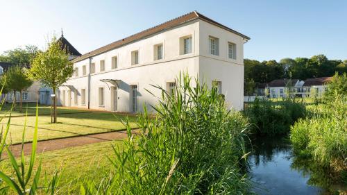 a white building with a river in front of it at Le Grand Pavillon Chantilly in Chantilly