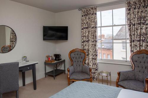 a bedroom with a bed and two chairs and a window at The Grosvenor Arms in Shaftesbury