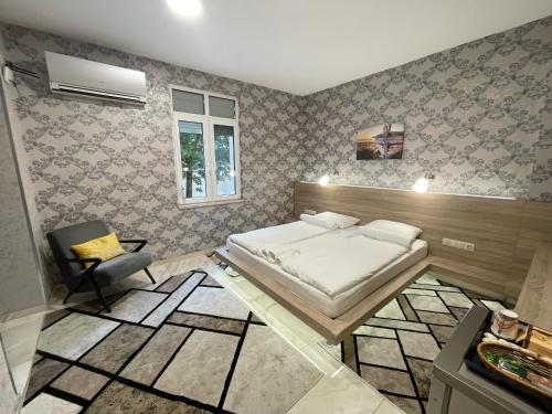 De Luxe Studio Burgas, City Center في مدينة بورغاس: غرفة نوم فيها سرير وكرسي