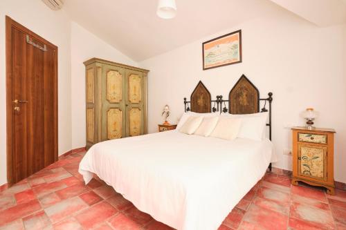 a bedroom with a white bed and a wooden cabinet at La Villetta in Pula