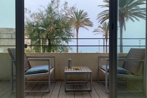 un balcon avec une table, des chaises et des palmiers dans l'établissement Fully equipped beachfront studio in the heart of the city center bd Leclerc, à Antibes