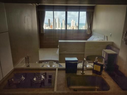 La salle de bains est pourvue d'un lavabo et d'une grande fenêtre. dans l'établissement Flat 26º andar com vista para o mar- Próximo ao shopping e à praia, à Récife
