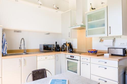 a kitchen with white cabinets and a sink at Au coeur de Tréffiagat - maison pour 6 - 300m de la plage in Tréffiagat