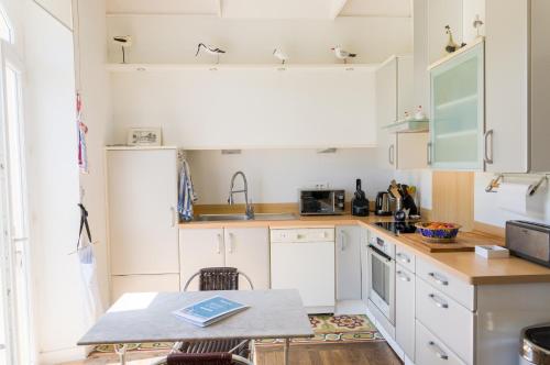 a small kitchen with white cabinets and a table at Au coeur de Tréffiagat - maison pour 6 - 300m de la plage in Tréffiagat