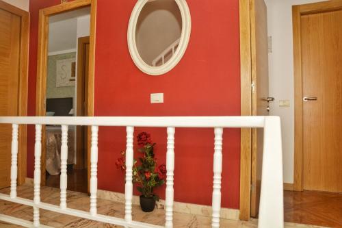 a staircase with a red wall and a round mirror at Hostal la Colegiata in Vigo