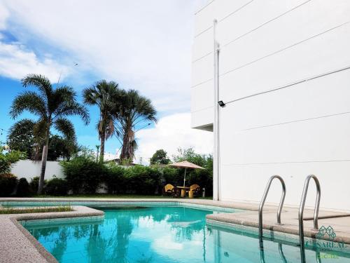 a swimming pool next to a white building with palm trees at Casareal Hotel by Cocotel in Concepcion