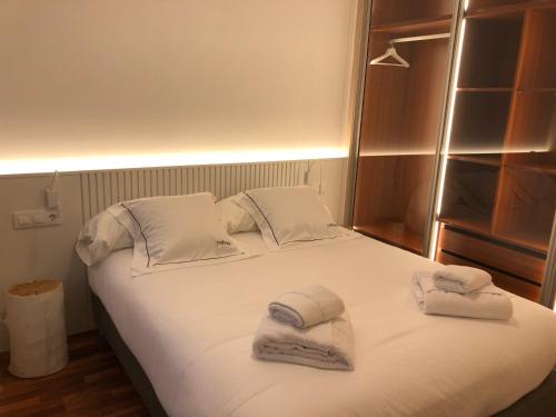 a bedroom with a bed with towels on it at Yuhom casas con alma Galera 2º in A Coruña