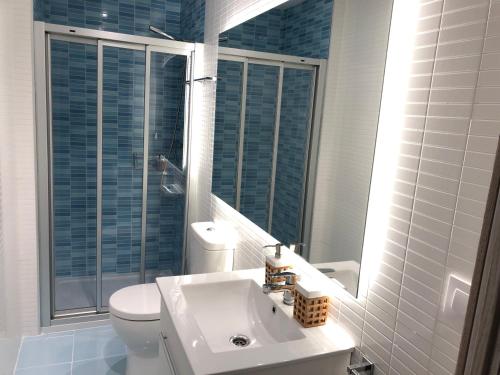 a bathroom with a sink and a toilet and a mirror at Yuhom casas con alma Galera 2º in A Coruña