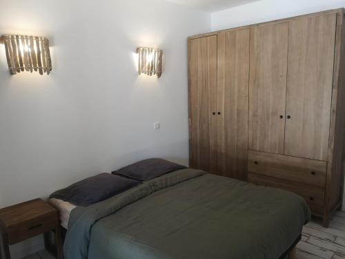 バルバッジョにあるAppartement Haute-Corse Calmeのベッドルーム1室(ベッド1台付)、木製キャビネットが備わります。