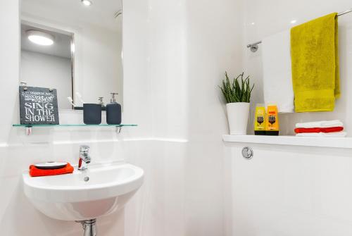 a white bathroom with a sink and a mirror at Yugo Explore - Arofan House in Cardiff