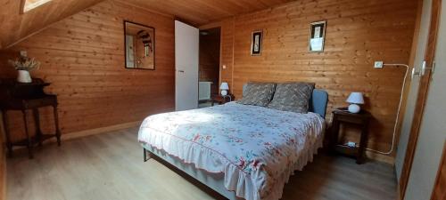 1 dormitorio con 1 cama y pared de madera en logement dans ferme equestre, en Lyons-la-Forêt