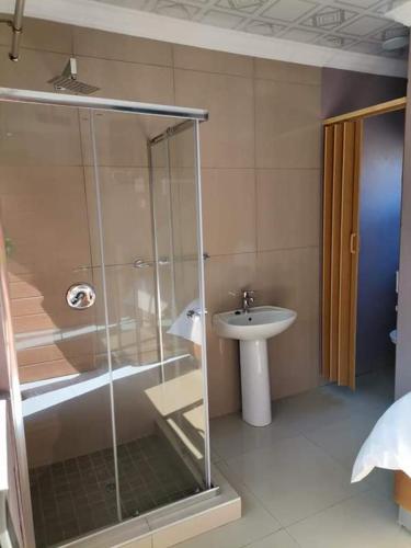 a bathroom with a glass shower and a sink at Sunset View Palace Guest House in Soshanguve