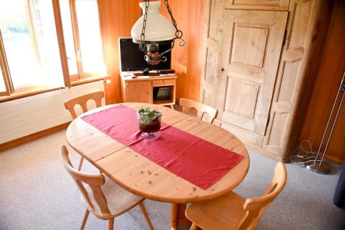 einen Holztisch in einem Zimmer mit einem roten Tischtuch darauf in der Unterkunft Haus Gerbi in Hasliberg