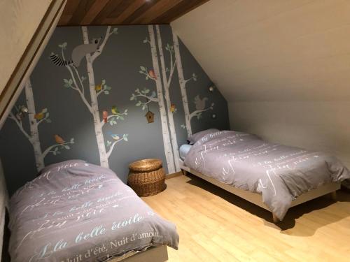 a bedroom with two beds and trees on the wall at La Grenaderie in Sergeac