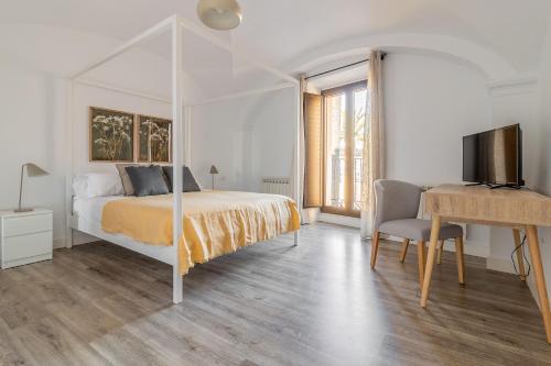 Dormitorio con cama, escritorio y TV en Apartamentos El Patio de Santa Clara, en Cáceres