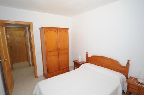 um quarto com uma cama e um armário de madeira em MADEIRA Orangecosta 1 dormitorio em Benicàssim