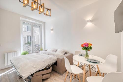 a white room with a bed and a table at HR Rambuteau - Châtelet in Paris