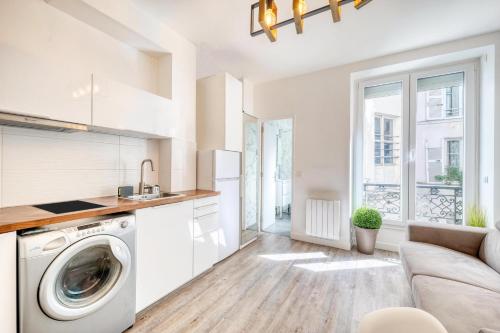 a kitchen with a washing machine and a couch at HR Rambuteau - Châtelet in Paris