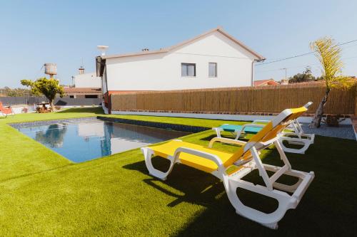 three lounge chairs sitting on the grass next to a pool at Santa Helena Apartments in Pombal