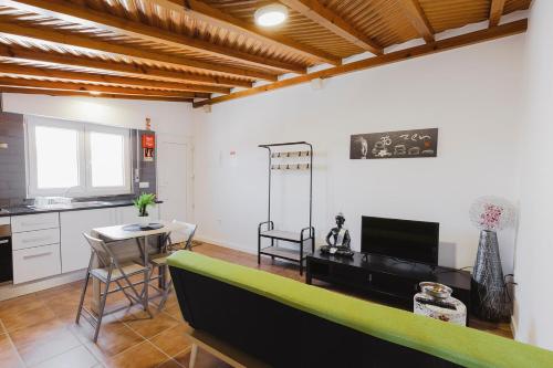 a living room with a green couch and a kitchen at Santa Helena Apartments in Pombal