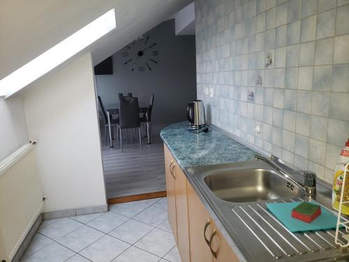 eine Küche mit einer Spüle aus Edelstahl und einem Tisch in der Unterkunft Apartament AGA13 in Mikołajki