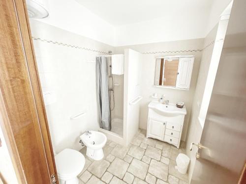 a white bathroom with a toilet and a sink at B&B La Vigna in Carovigno