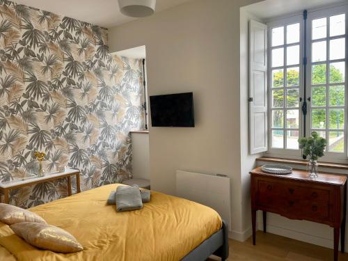 1 dormitorio con 1 cama amarilla y TV en La Seigneurie des Ondes, en Saint-Benoît-des-Ondes