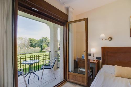 a bedroom with a bed and a balcony with a table and chairs at Hotel Rural Campaniola in Pontevedra