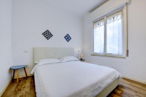 une chambre blanche avec un grand lit blanc et une fenêtre dans l'établissement Appartamento Cesare, à Sirmione