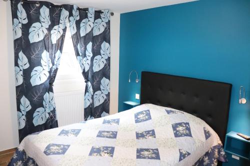 een slaapkamer met een bed met een blauwe muur en een raam bij Gîte les Eglantines Rez-de-Jardin in Gérardmer