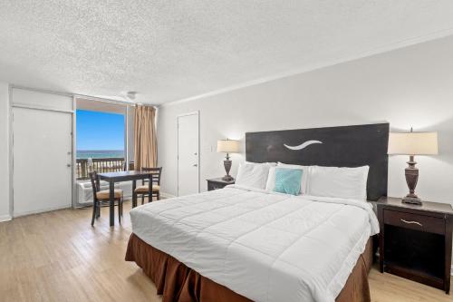 a bedroom with a large bed with a desk and a table at The Reef At Seahaven Beach Resorts in Panama City Beach