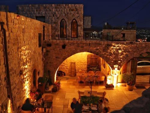 a stone building with a patio with tables and chairs at Chateau du Roi in Mi‘ilyā