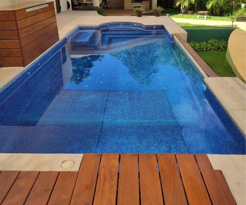 a blue swimming pool with a wooden deck at Azcapri Villa Boutique & Spa in Cancún