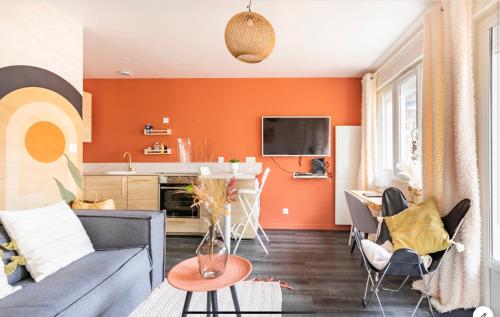 a living room with an orange accent wall at Le 102, Maison avec Terrasse et parking Gare de ROUEN in Rouen